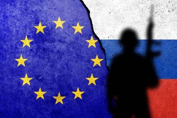 Flag of Europe Union and Russia painted on a concrete wall with soldier shadow. Relationship between EU and Russia