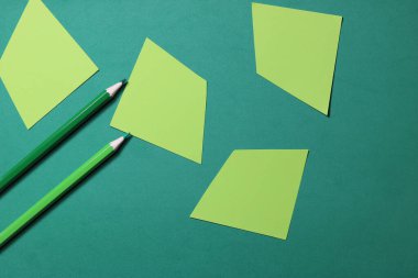 Geometrik şekilli yeşil kağıt üzerindeki kalemler. Çizim konsepti