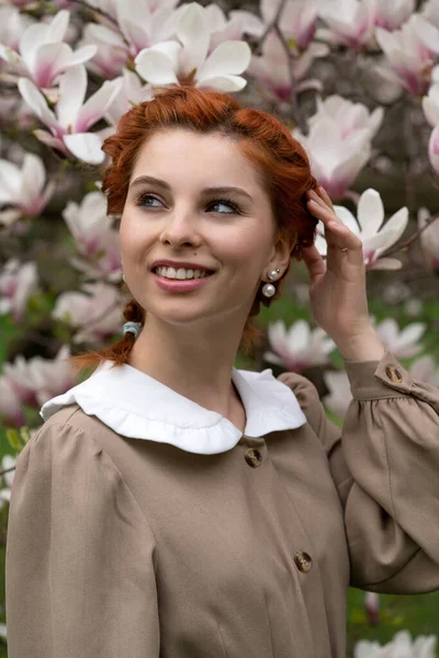 Lüks manolya çiçekleri içinde güzel bir kız. Parkta ilkbahar. Gençler ve gençler. Kadın modası. Aşkı bekliyorum. Temiz havadaki cazibe ve şefkat. Eski tarzda güzel bir elbise.