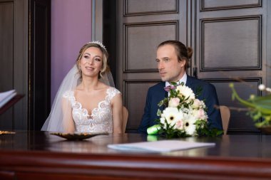 Evlilikten. Beyaz gelinlik ve mavi takım elbiseli genç gelin ve damat. Evlilik ve nişan yüzükleri. Yeni evliler çifti. Sadakat ve sevgi yemini. İnsanların hayatlarında önemli bir olay