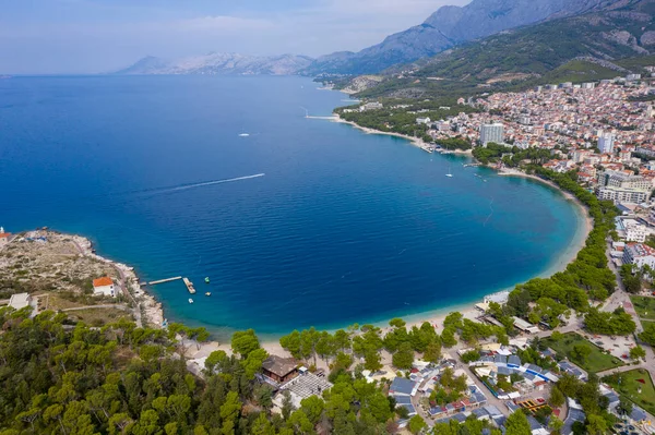 View of the harbor and city. Makarska riviera.Dolmatia.Blue south sea. Mountains, houses, yachts, ships, boats on the pier. City beach and pier. Drone footage. Summer. Adriatic. Relax. Vacation. The beauty.