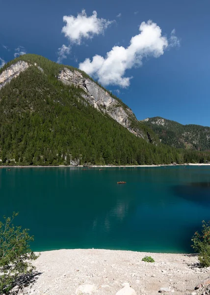 Lots of wooden boats in a picturesque, blue Braies lake.Logo di Braies Pragser Wildsee in Italy.  Alps. Dolomites mountains in South Tyrol Coniferous forest. Blue sky with clouds. Tourist place. High mountains.