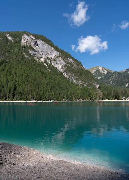 Lots of wooden boats in a picturesque, blue Braies lake.Logo di Braies Pragser Wildsee in Italy.  Alps. Dolomites mountains in South Tyrol Coniferous forest. Blue sky with clouds. Tourist place. High mountains.