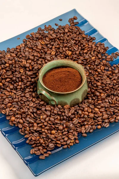 Ground coffee in a green jug. A lot of coffee grains on a glass blue dish. Invigorating drink. Vigor for the whole day. Morning coffee. Aroma. Breakfast. Caffeine. Energy in the morning