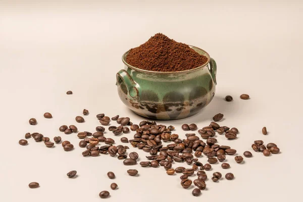 A green cup with ground coffee a lot of coffee grains on a white background are an invigorating drink. Vigor for the whole day. Morning coffee. Aroma. Breakfast. Caffeine. Energy in the morning. Good morning.