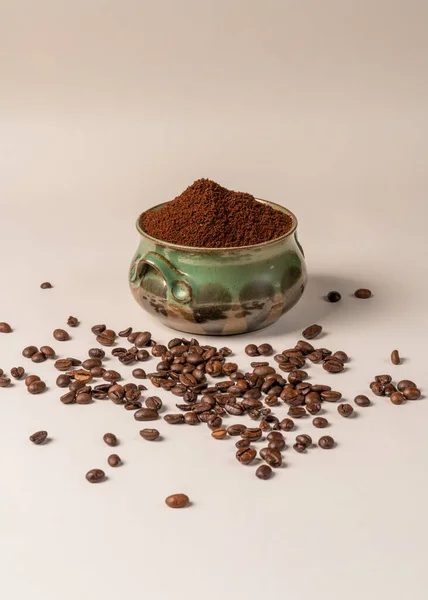 A green cup with ground coffee a lot of coffee grains on a white background are an invigorating drink. Vigor for the whole day. Morning coffee. Aroma. Breakfast. Caffeine. Energy in the morning. Good morning.