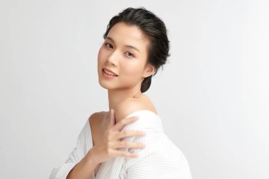 Beyaz arkaplanda bornoz, yüz bakımı, yüz bakımı, kozmetoloji, güzellik ve spa konsepti olan güzel Asyalı bir kadın..