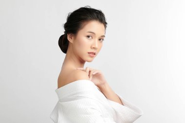 Beyaz arkaplanda bornoz, yüz bakımı, yüz bakımı, kozmetoloji, güzellik ve spa konsepti olan güzel Asyalı bir kadın..