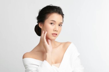 Beyaz arkaplanda bornoz, yüz bakımı, yüz bakımı, kozmetoloji, güzellik ve spa konsepti olan güzel Asyalı bir kadın..