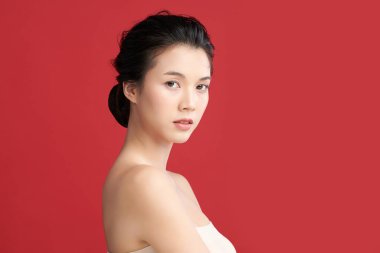 Güzel genç Asyalı kadın, kırmızı arka planda temiz ten, yüz bakımı, yüz bakımı, kozmetoloji, güzellik ve kaplıca, Asyalı kadın portresi..