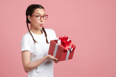 Mutlu genç bayan pembe arka planda hediye kutusu tutuyor, reklam içeriğiniz için boş fotokopi alanı.