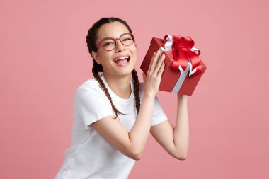 Mutlu genç bayan pembe arka planda hediye kutusu tutuyor, reklam içeriğiniz için boş fotokopi alanı.