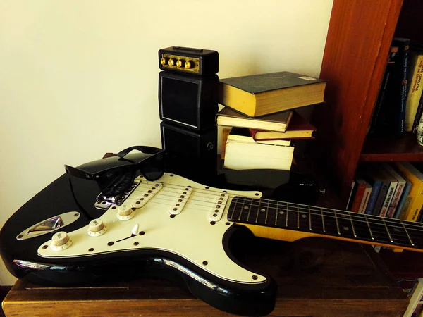 本とブースターに囲まれたテーブルの上のエレキギター — ストック写真