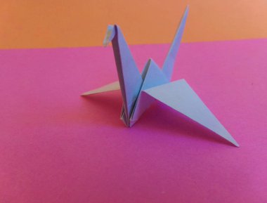 Pembe ve düzenleyici arka planda bir kağıt vinç..