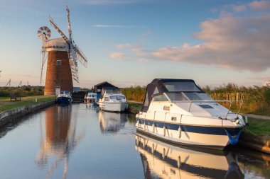 Güneş doğarken Horsey Mill 'in yanındaki Norfolk kadınlarına demirlemiş tekneler.