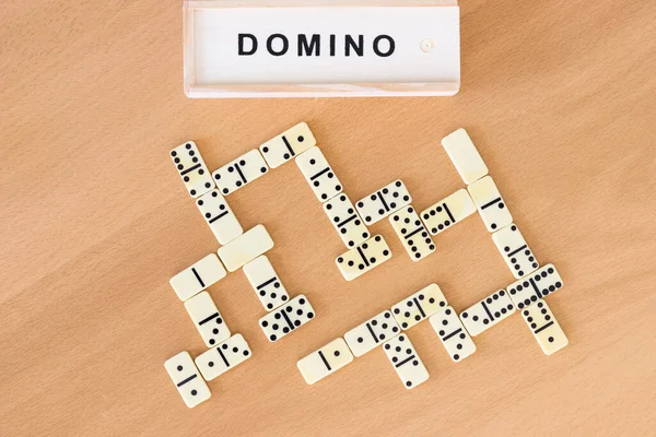 Tahta bir arka planda dizilmiş domino taşları ve kutular.