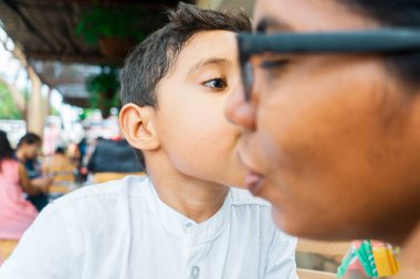 Latin oğlu lokantada annesini yanağından öpüyor.