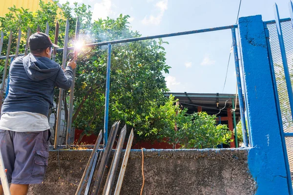 Modrý obojek pracovník z Latinské Ameriky vidět zezadu svařování plot — Stock fotografie