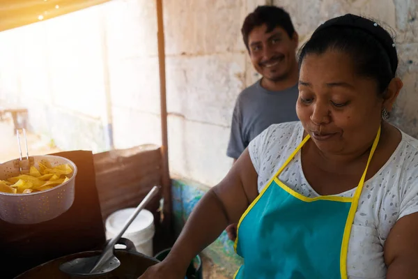 A Latin woman tends her retail business on the street and cooks fried sliced plantains — Photo