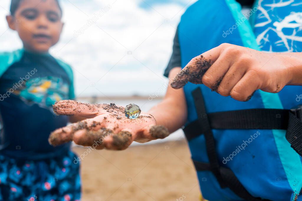 Latin boy showing his brother a marble in his hand, a treasure he found digging on the beach during spring breake in Nicaragua.