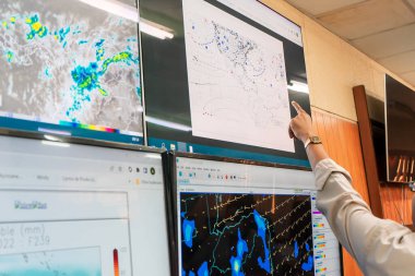 Weather prediction by an unrecognizable scientist pointing at the graphs on a screen. clipart