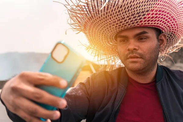 Latin bir adamın cep telefonuyla selfie çektiği ve Masaya, Nikaragua 'da egzotik bir turizm merkezinde renkli bir şapka taktığı portre..