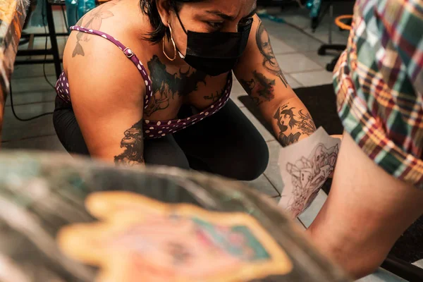 Latina tattoo artiest zetten een schets van een tatoeage op haar klanten been in een studio in Managua — Stockfoto