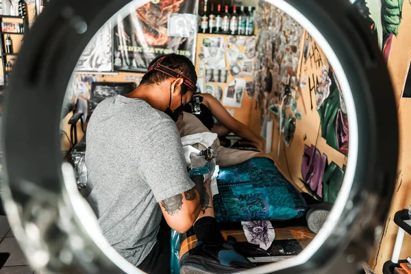 Latynoski Artysta Tatuażu Pracuje Nad Projektem Widzianym Wnętrza Pierścienia Światła — Zdjęcie stockowe