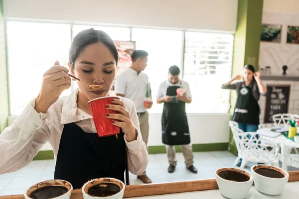 Profesyonel kahve makinesi altın kaşıkla özel bir fincanı inceliyor.