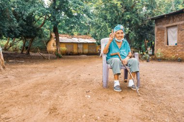 Plastik sandalyede oturan yaşlı Latin bir kadın, Rivas Nikaragua 'nın kırsal kesimindeki küçük evinde barış jesti yapıyor...