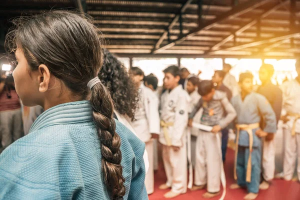 Unrecognizable Latin girl seen from behind in a gym full of child judo fighters in Managua Nicaragua