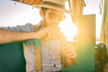 Barda puro yakan şapkalı ve pantolon askılı genç bir hippi.