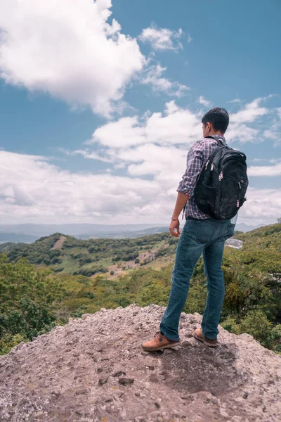 Young Latin student man seen from behind exploring the city with his eyes