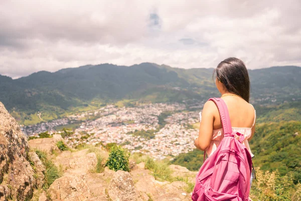 Latina college student girl from the back looking toward the city from a high place
