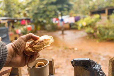 Closeup to the hands of a latin man with empanadas and donuts with coffee, traditional snack from Nicaragua