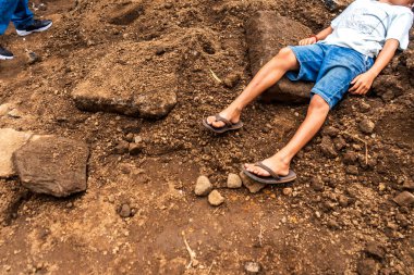 Child victim of a natural disaster lying in some rubble in Latin America