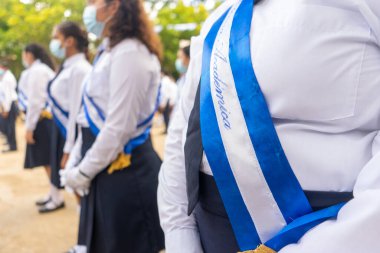 Outstanding student girls with honor band of academic excellence written in spanish standing in rows in Managua, Nicaragua