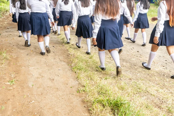 Group of high school student girls walking and wearing uniforms in a rural area of Latin America