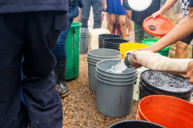 Poor families supplying drinking water with a hose in bucket in latin america