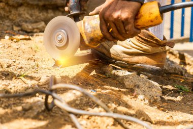 Closeup on the hand of a Latin man cutting a metal bar with a circular electric hand saw in south america