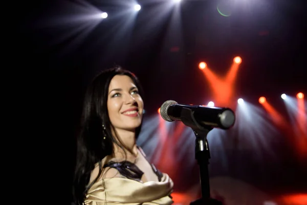 Young woman with microphone in hand on entertainment event.