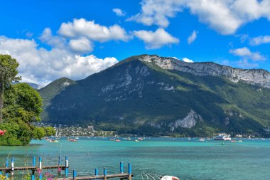 Lake of Annecy with pontoons, boats and mountain from the edge