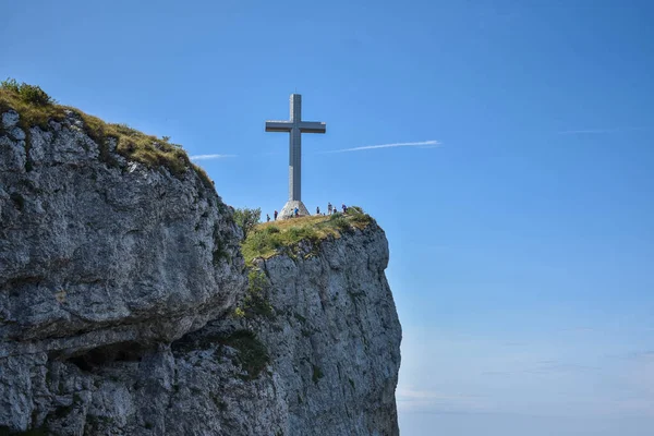 Mavi gökyüzü olan bir dağdaki haçın alçak açılı görüntüsü.