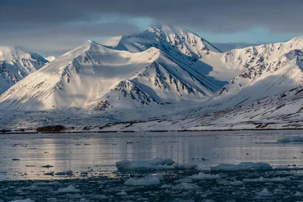 Besneeuwde bergen met pieken in de wolken. In Spitsbergen, Noorwegen. Opwarming van de aarde. — Stockfoto