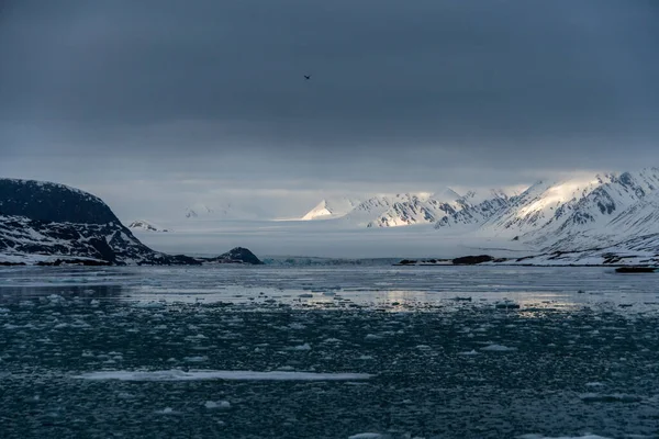 Besneeuwde bergen met pieken in de wolken. In Spitsbergen, Noorwegen. Opwarming van de aarde. — Stockfoto