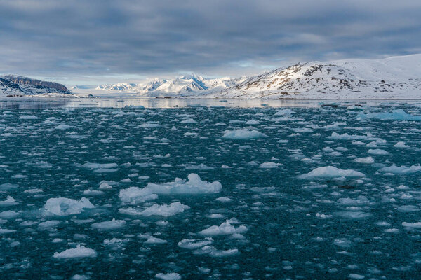 Snowy mountains with peaks in the clouds. In Svalbard, Norway. Global Warming.