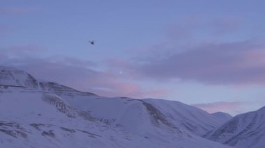 Helikopter Svalbard 'ın karlı dağlarının üzerinde..