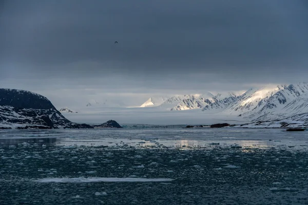 Bulutlarda tepeleri olan karlı dağlar. Svalbard, Norveç 'te. Küresel ısınma.