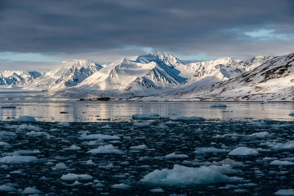 Śnieżne góry z szczytami w chmurach. W Svalbard, w Norwegii. Globalne ocieplenie. — Zdjęcie stockowe