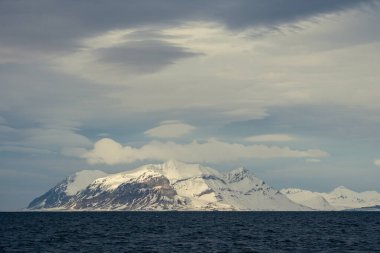 Norveç, Svalbard 'da dağların mavi saatinin panoramik manzarası, kar ve deniz.